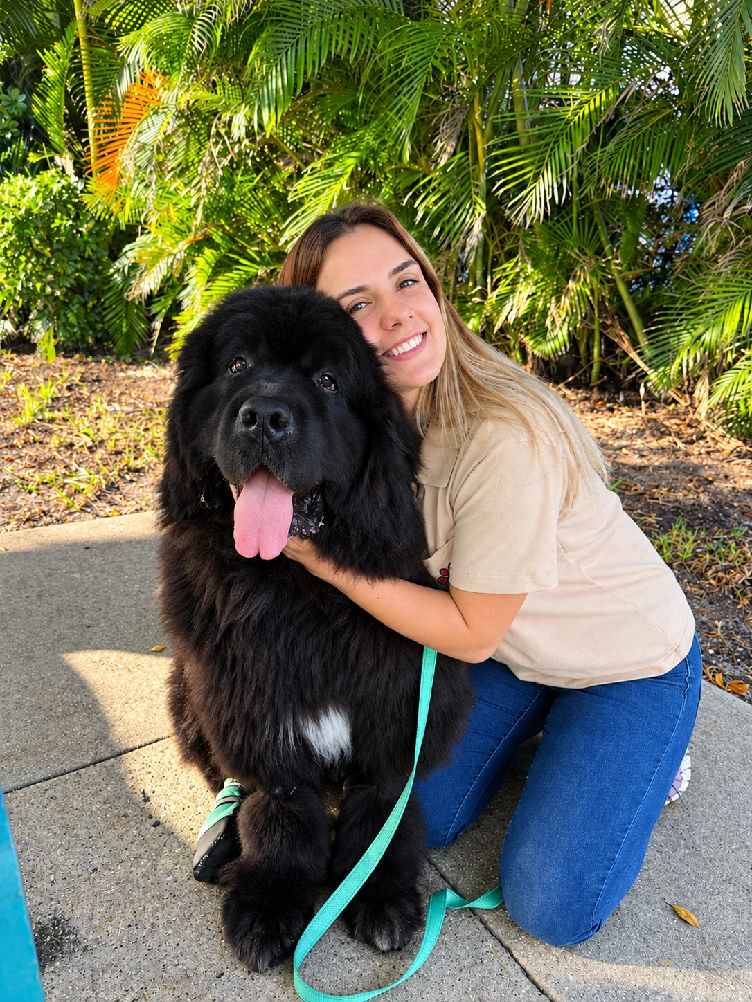 Vitoria Fernandes smiling and hugging a large black dog outdoors